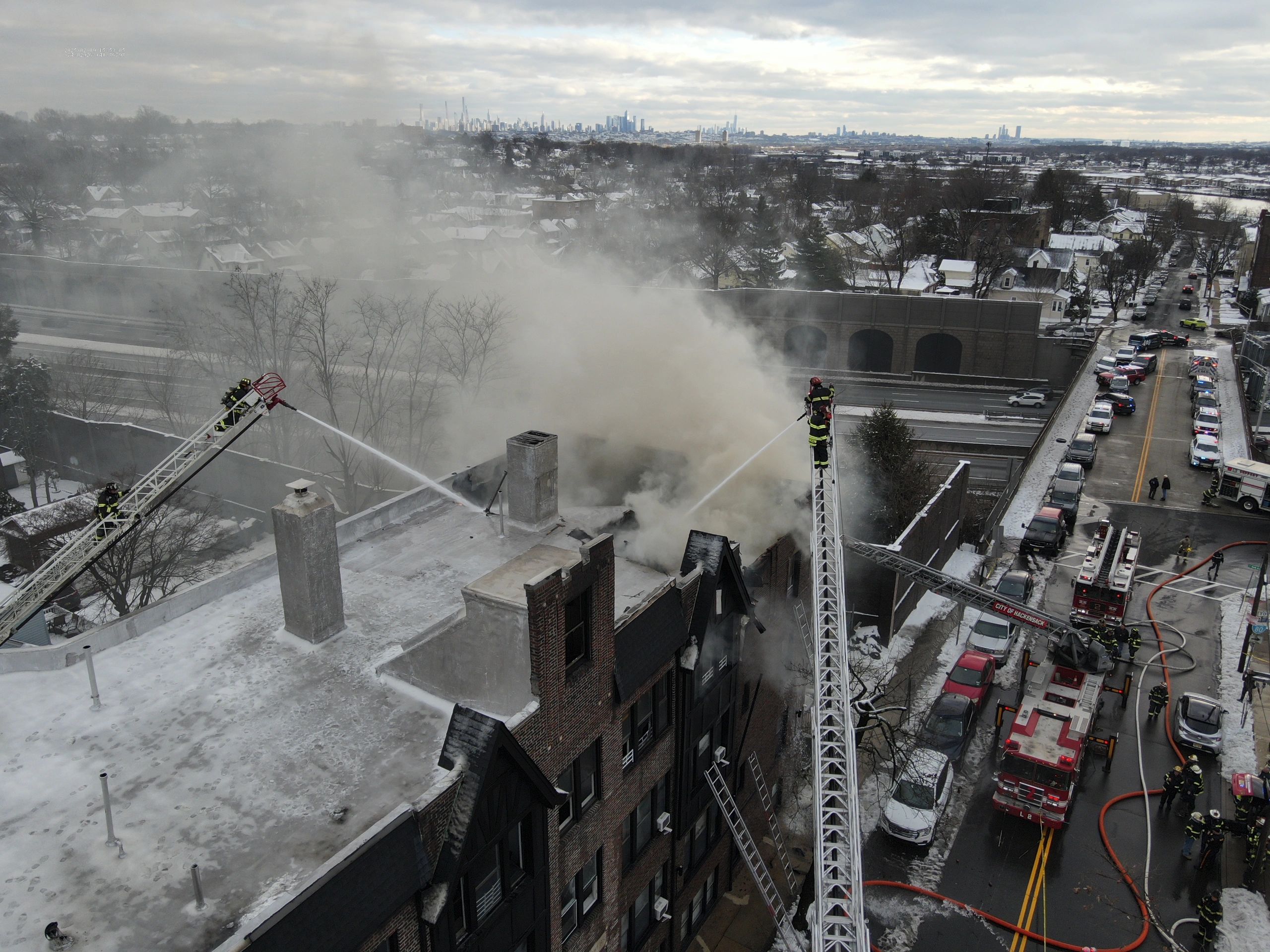 Firefighters battle a large building fire with smoke billowing.