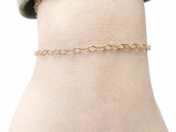 Delicate gold chain anklet on a person's ankle.