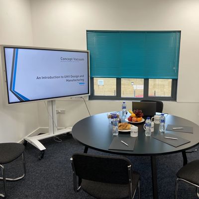 Training session room with presentation on screen and snacks and mugs on the table. 
