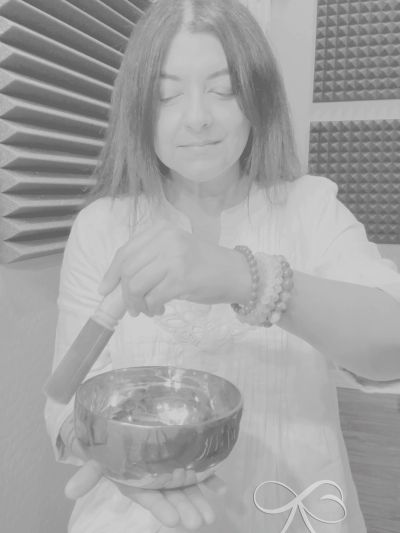 artist using a singing bowl with closed eyes in a calming environment.