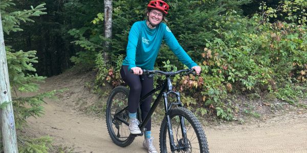 Person smiling on a bike in a forest trail.