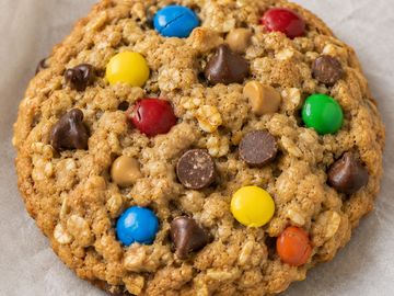 Close-up of an oatmeal cookie with colorful candy-coated chocolates and chocolate chips.