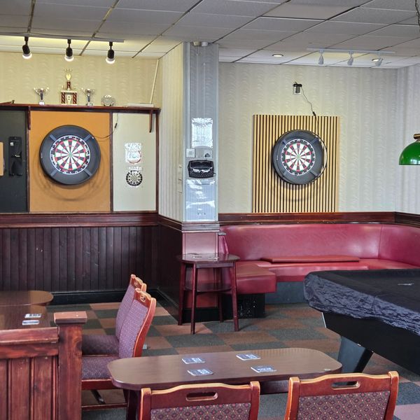 Cozy game room with dartboards, pool table, and seating area.
