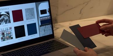 Person comparing paint swatches with materials on a laptop screen.