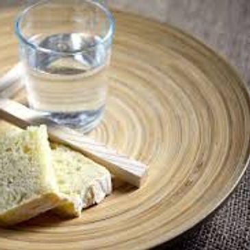 Glass of water and bread slices on a wooden plate.
