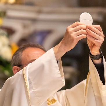 A priest elevates the communion host during a religious ceremony.