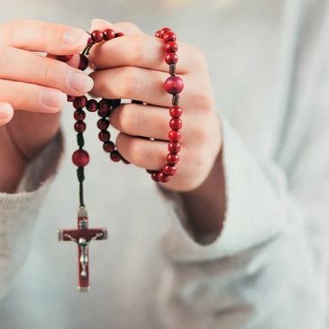Hands holding a wooden rosary with a crucifix.