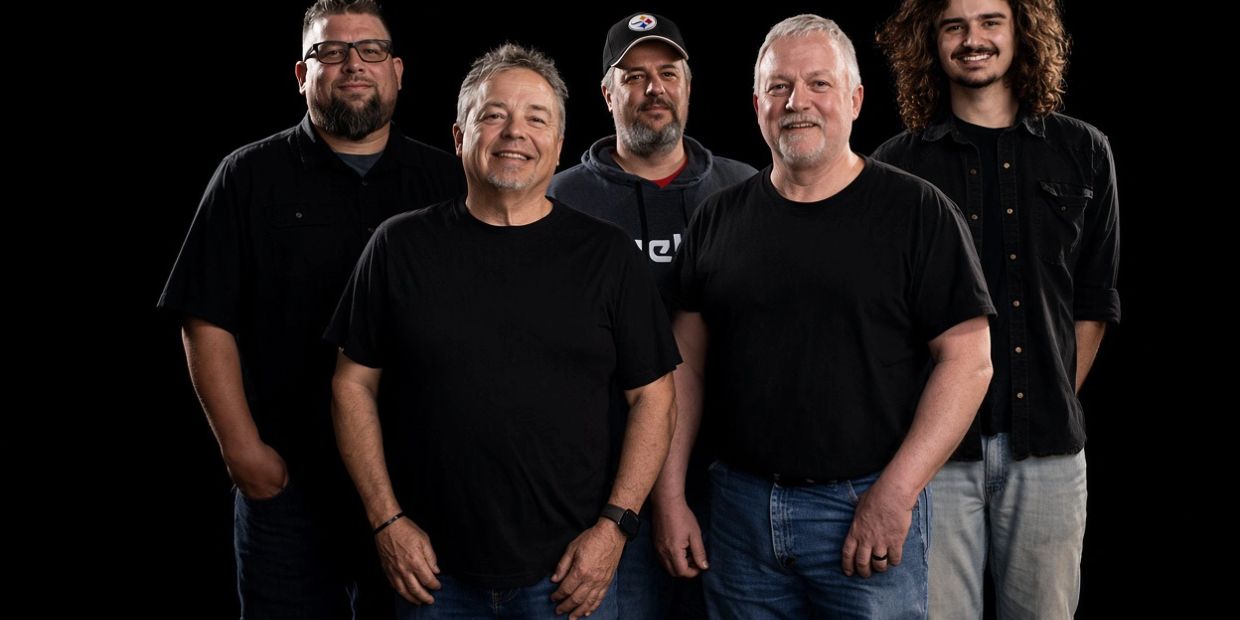 Group of five men posing against a black background.