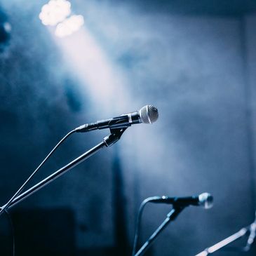 Two microphones on stands under stage lighting with a smoky atmosphere.