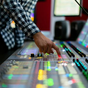 Person adjusting controls on a colorful sound mixing console.