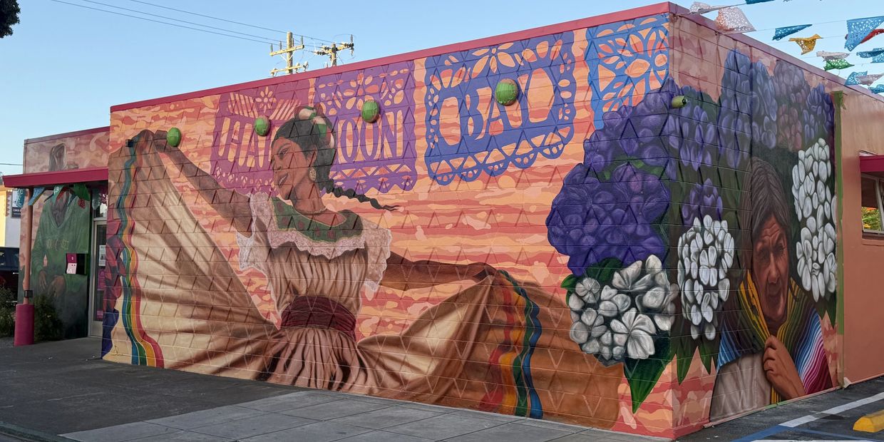Colorful mural of dancer and flowers on building corner.