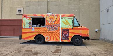 Bright orange food truck parked outdoors.