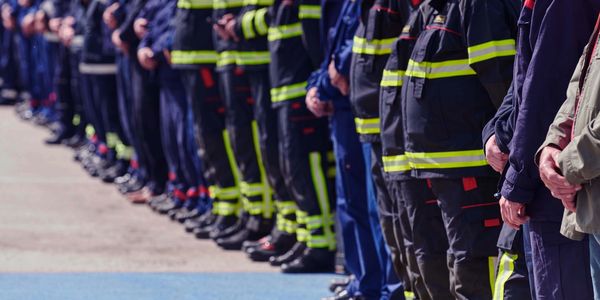 People standing in a long line wearing uniforms and safety gear.