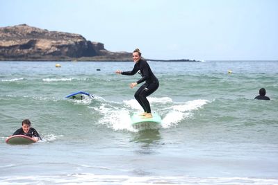 People learning to surf and practicing with surfboards on the beach and in the ocean in Essaouira