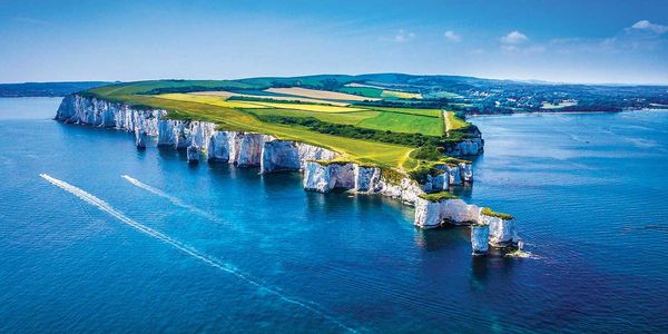 A scenic island with cliffs surrounded by blue sea under a clear sky.
