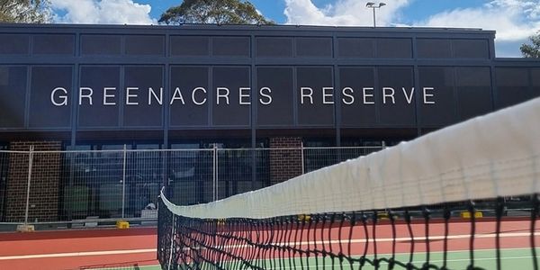 Tennis court at Greenacres Reserve under blue sky.