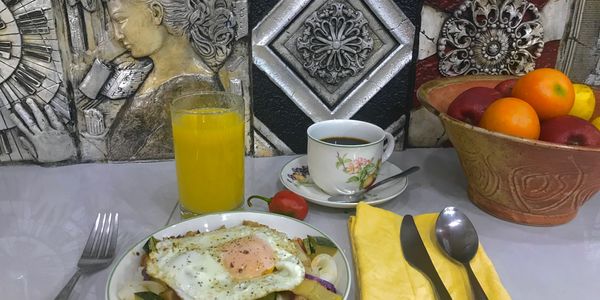 Un desayuno sencillo: huevo frito, ensalada fresca, jugo natural y café recién hecho.