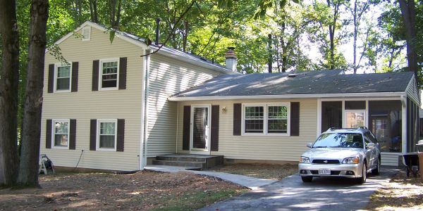 Two-story beige house with a car parked outside.
