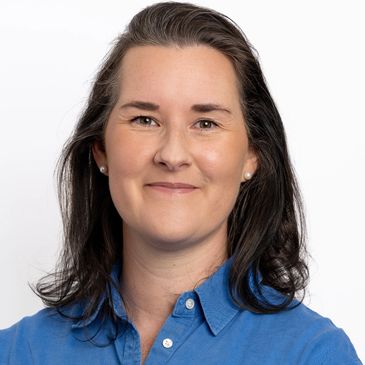 Woman with shoulder-length dark hair in a blue shirt smiling.