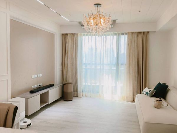 Bright, minimalistic living room with beige tones and a modern chandelier.