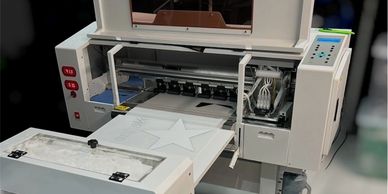 A digital flatbed printer producing a star design on a flat surface.