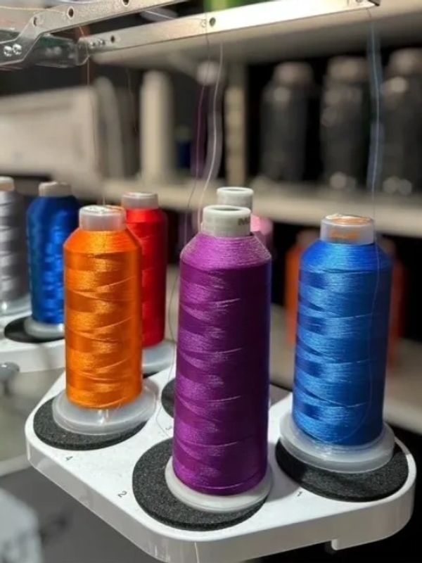 Colorful spools of thread on a sewing machine attachment.