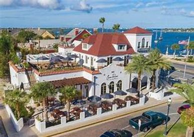 A coastal restaurant with outdoor seating and red-roofed buildings by the water.