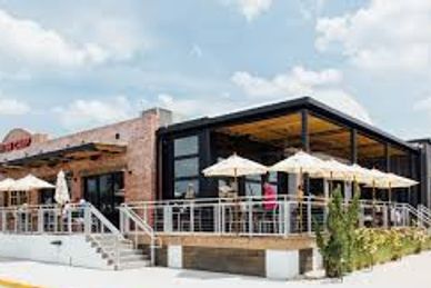 Modern café with outdoor seating and umbrellas on a sunny day.