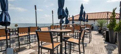 Empty outdoor patio seating with closed umbrellas on a sunny day.