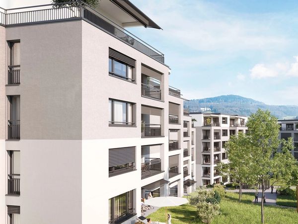 Modern apartment buildings with balconies and greenery in a sunny setting.