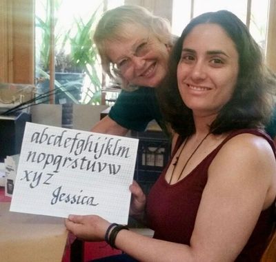 a photo of the teacher Susan Mae Hull with her student holding a completed calligraphy alphabet