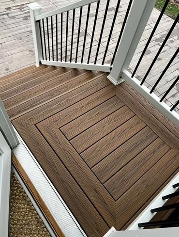 Intricately patterned wooden deck with white railing and black balusters.