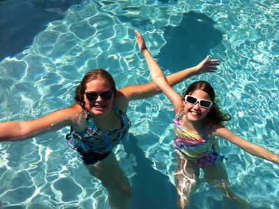 Two girls wearing sunglasses enjoying a sunny day in the pool.