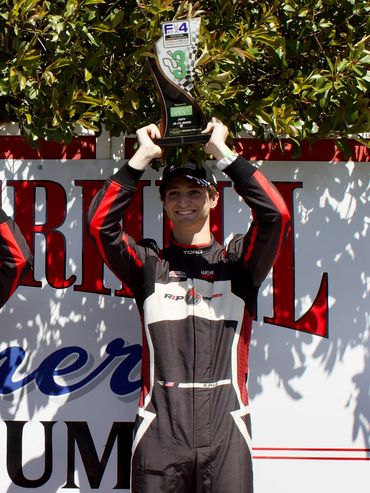 Race car driver celebrates with a trophy.
