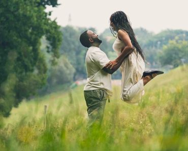 Couple joyfully embracing in a lush green meadow.