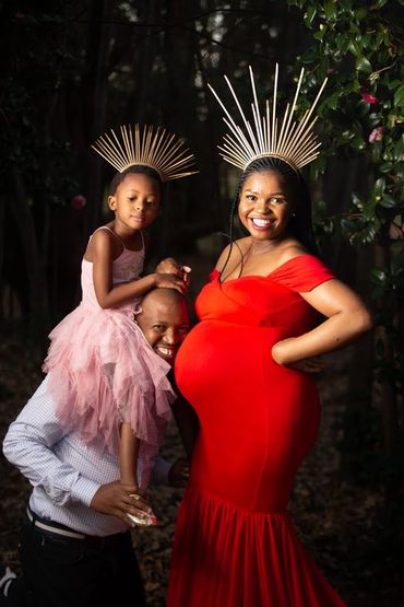 Family celebrating pregnancy with matching headpieces in a forest.