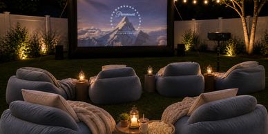 Cozy backyard outdoor movie night setup with comfy chairs and string lights.