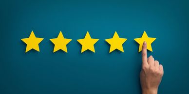 Hand pointing at the fifth star in a five-star rating.