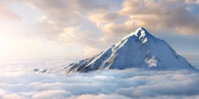 Snow-covered mountain peak rising above clouds at sunrise.