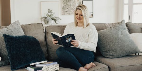 a woman sitting on the couch is reading a book 