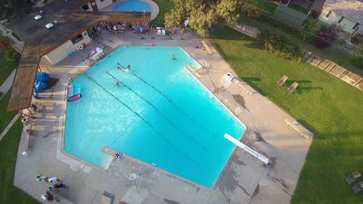 Aerial view of a swimming pool with swimmers and a diving board.