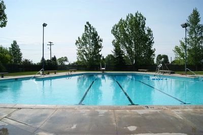 Outdoor swimming pool with clear water and trees in the background.