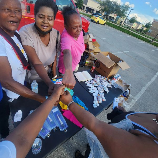 Group fist bump over a table with supplies outdoors.