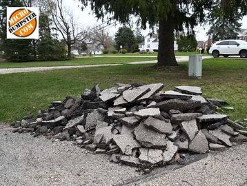 A pile of broken asphalt chunks removed from a driveway, stacked and ready for hauling
