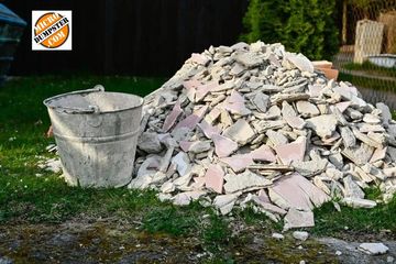 A bucket next to a pile of plaster in a ready to be loaded into the Micro Dumpster 3.5 Dirt dumpster