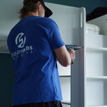 Professional removals employee dismantling a wardrobe 