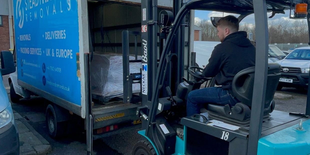 Forklift loading a pallet of goods into a removals van in Guildford.