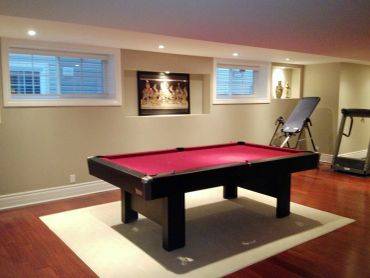 Modern basement with red pool table and exercise equipment.