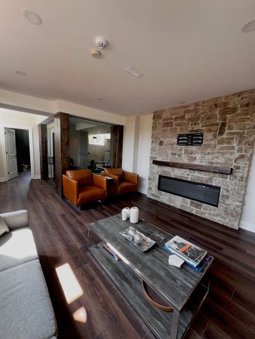 Modern living room with stone wall and brown chairs.