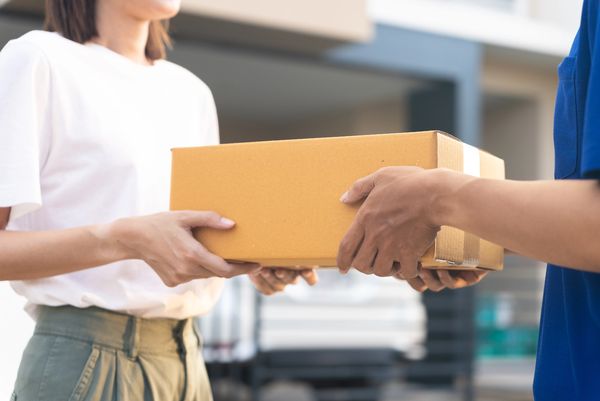 Close-up of hands exchanging a cardboard package.